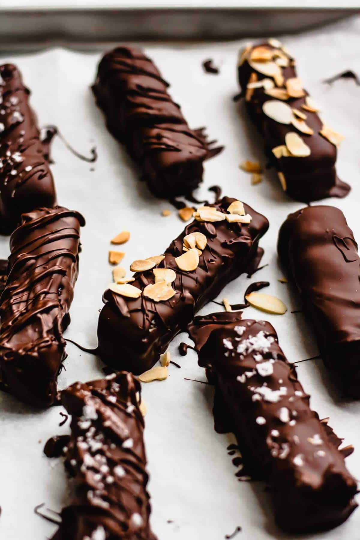 Caramel bars coated with chocolate with flaked almonds and salt on top.