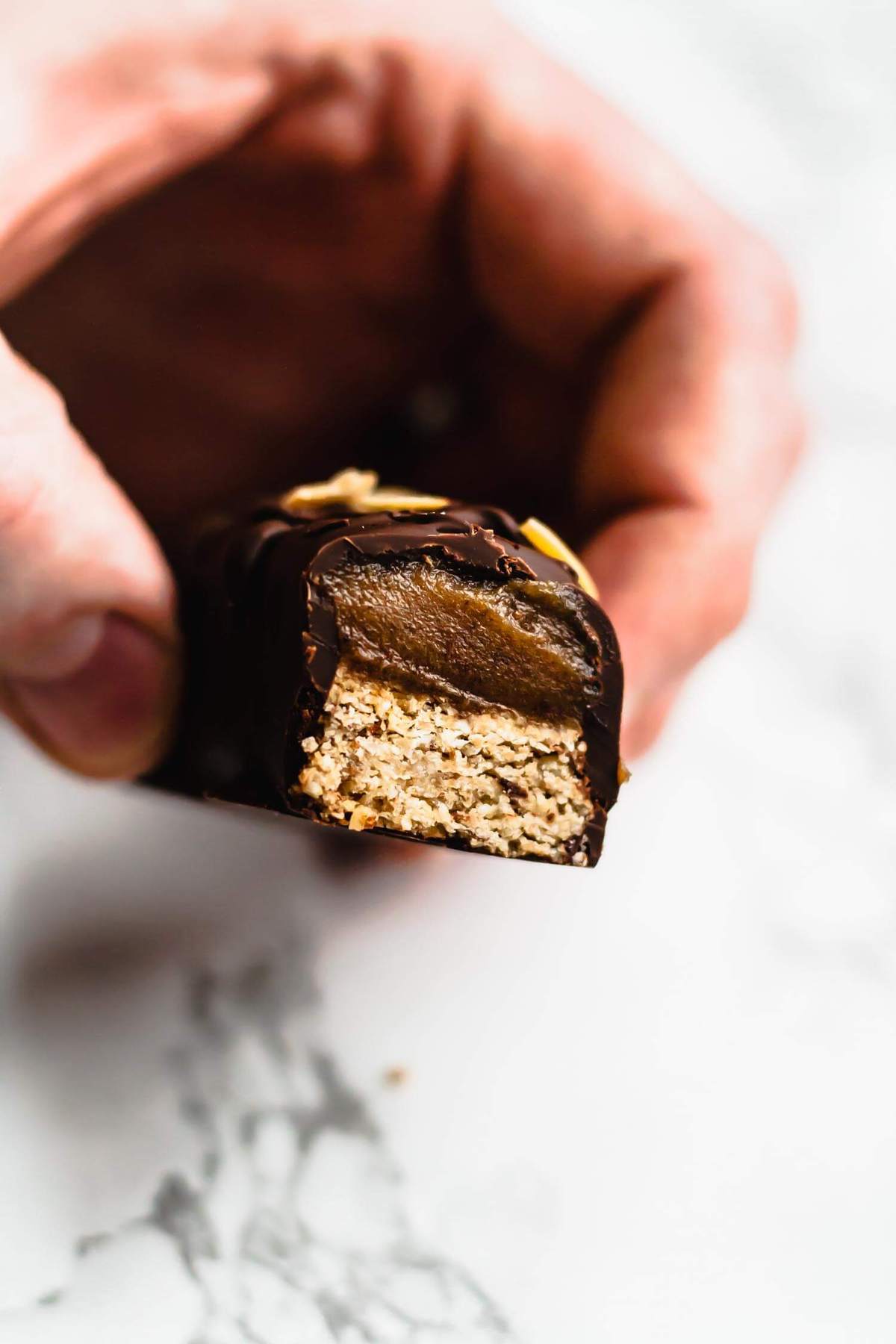 Half eaten caramel chocolate bar being held.