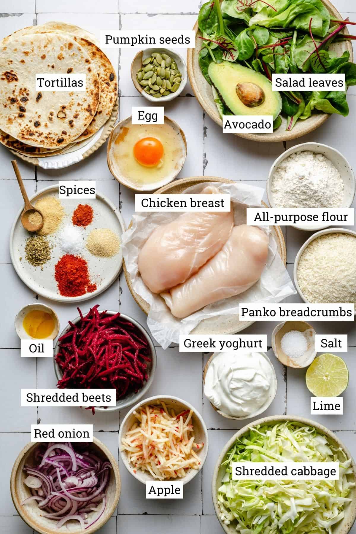 Ingredients for chicken tacos in various bowls on a white tile background.