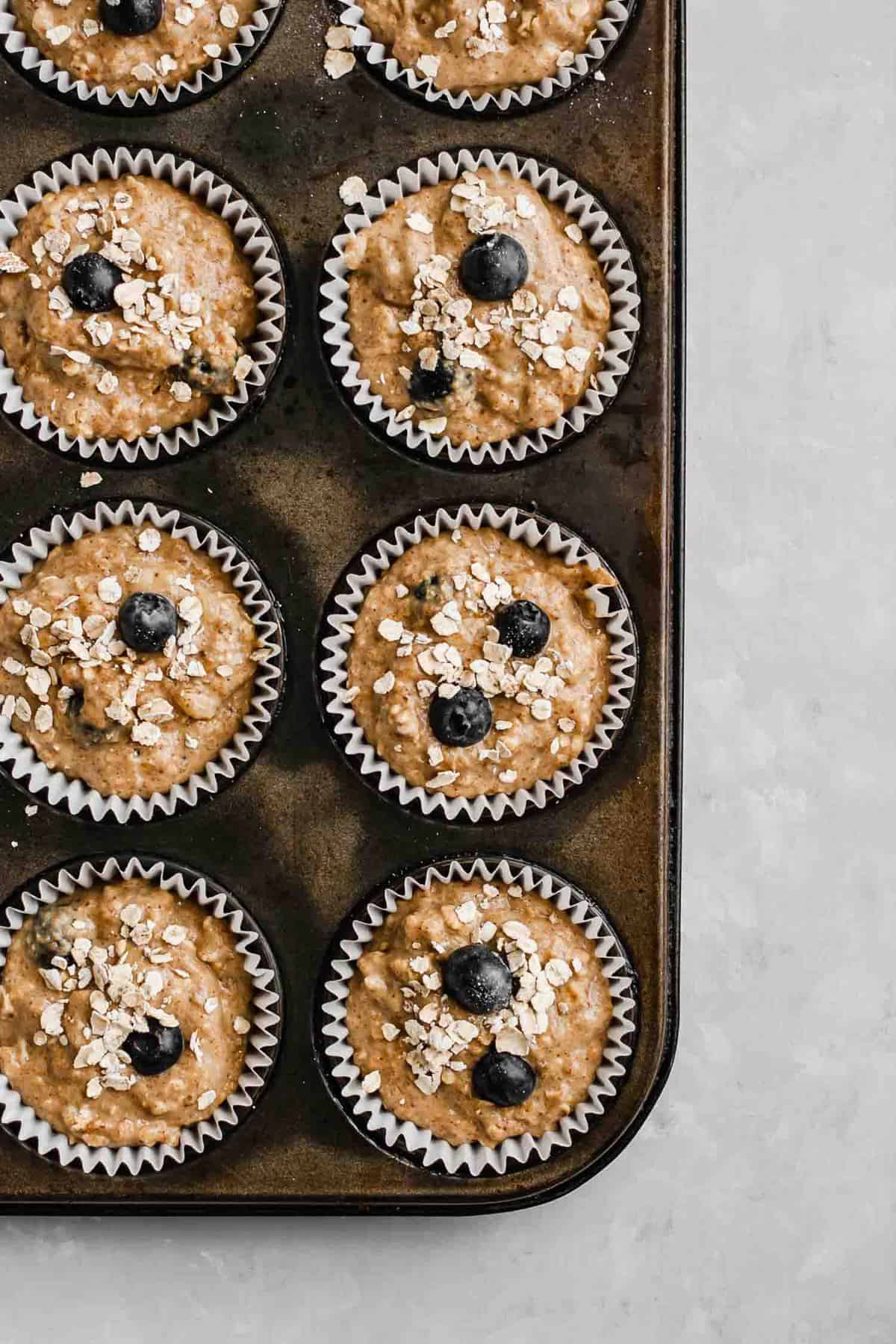 Pre baked blueberry muffins in cases in a muffin tray.