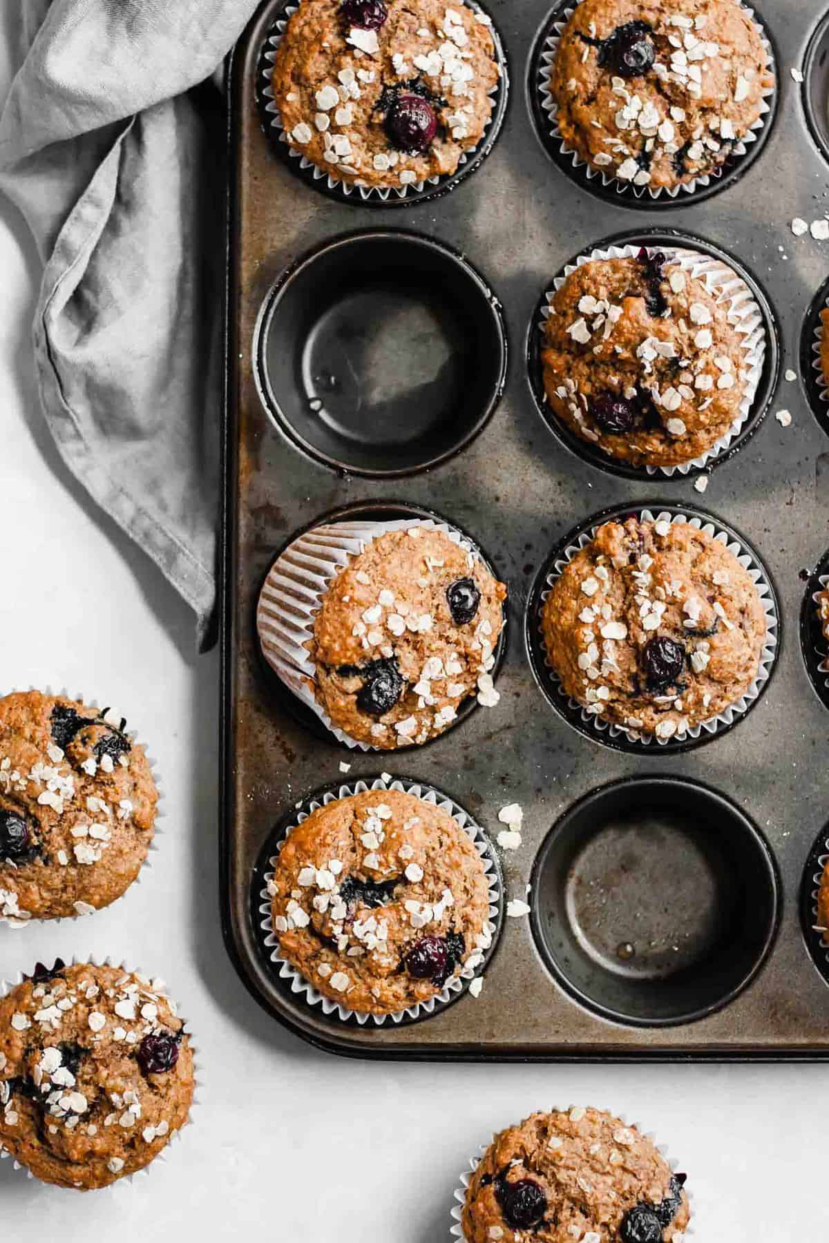An array of blueberry muffins with oats and blueberries on top.