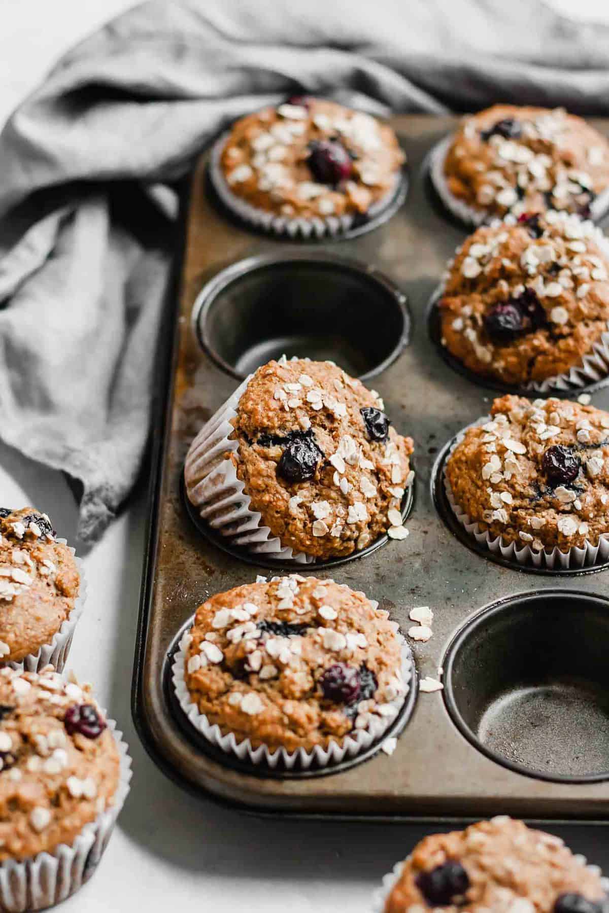 Various blueberry muffins baked on a muffin tray and napkin.