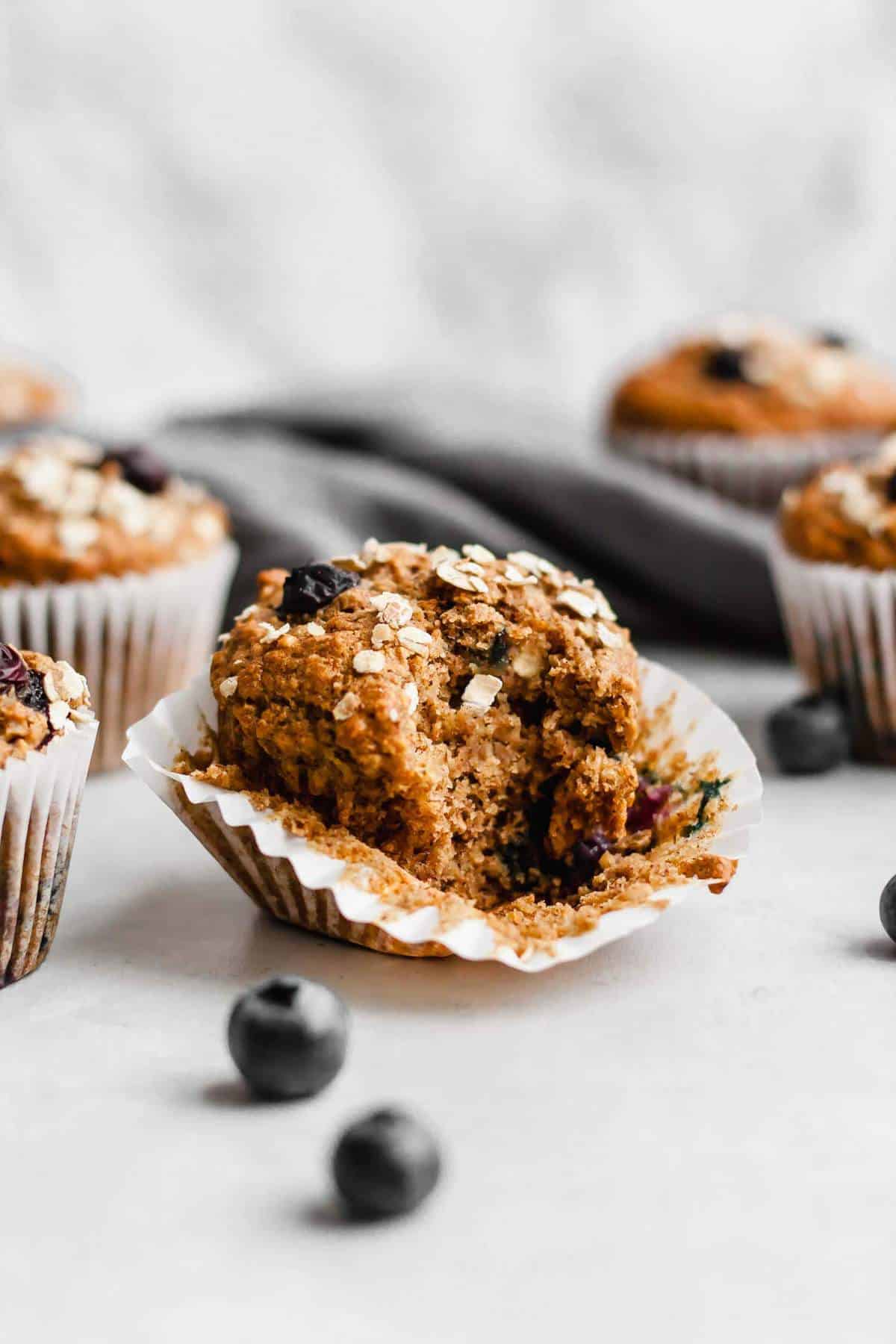 Blueberry muffin with case peeled back and a bite taken out showing the inside.