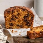 A cut open chocolate chip zucchini bread on a baking tin with a knife.