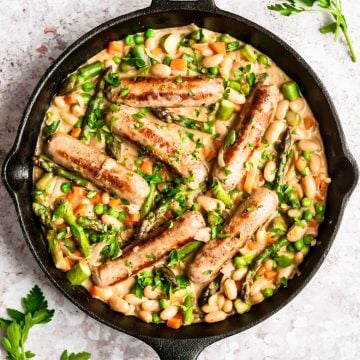 shot of finished dish of creamy chicken sausages and vegetables in a cast iron skillet