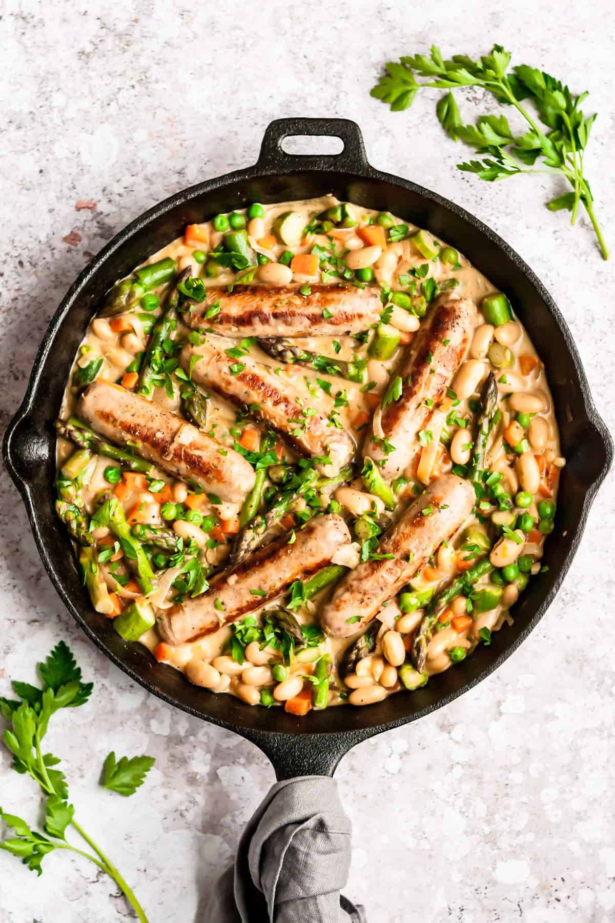 shot of finished dish of creamy chicken sausages and vegetables in a cast iron skillet