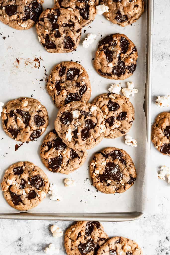 a sheet pan with lots of popcorn chocolate chip cookies and popcorn scattered around