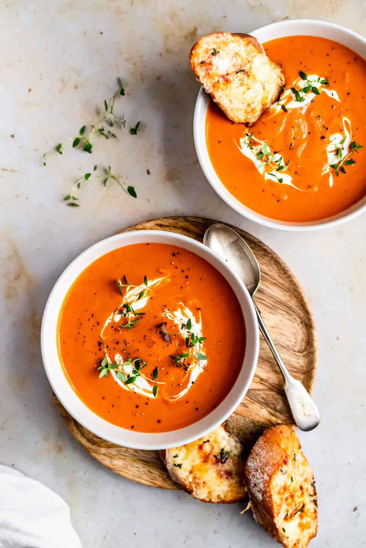 A bowl of butternut squash and red pepper soup with yoghurt swirls and a spoon 