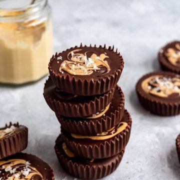 stack of cashew butter cups with a jar of cashew butter in the background