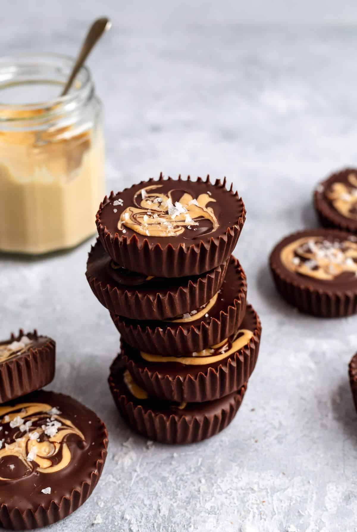 a stack of cashew butter cups with a jar of cashew butter in the background