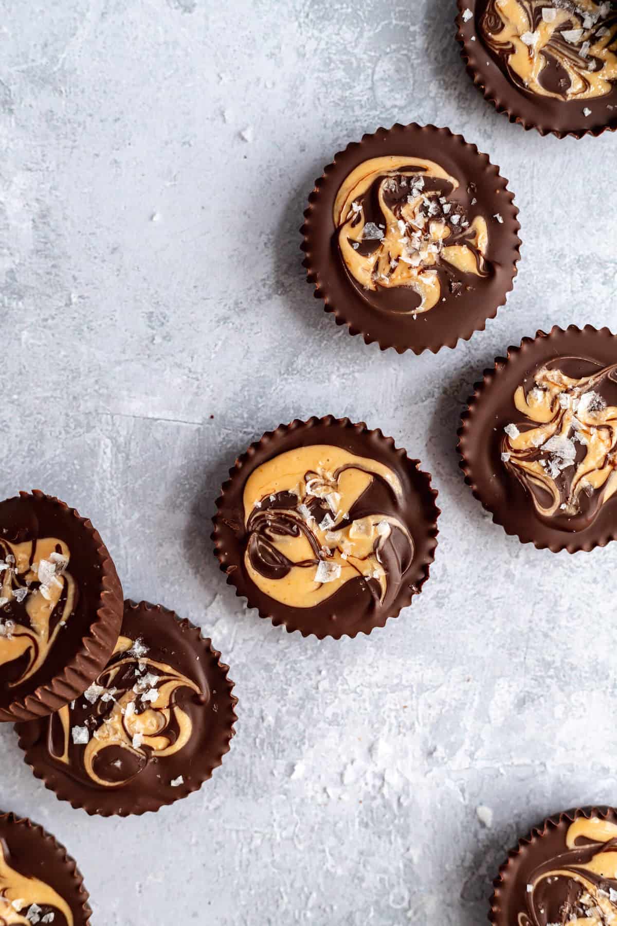 a close up of cashew butter cups with a cashew butter swirl and flaked sea salt on top