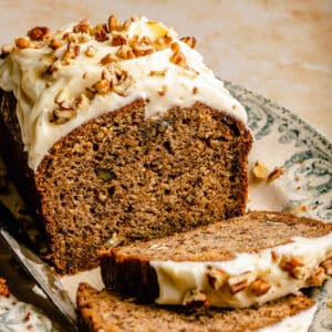 A close up of banana pecan bread on a platter cut open with a few slices falling away.