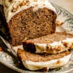 Banana pecan bread on a platter with a couple of slices falling away.