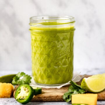 Pineapple chicken marinade in a jar with lime, pineapple and jalapeno around it.