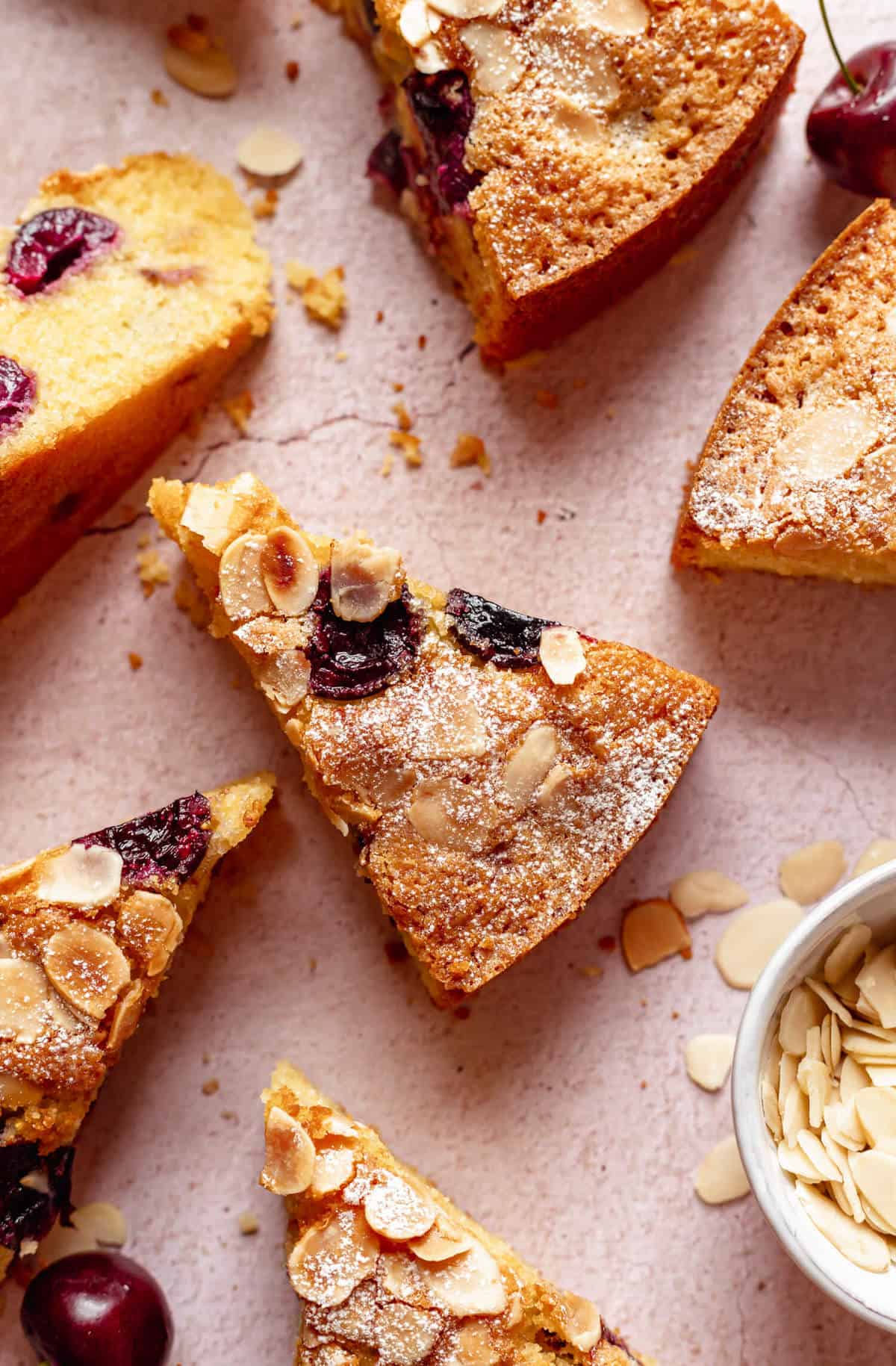 close up of a slice of cherry almond cake with a few slices scattered around