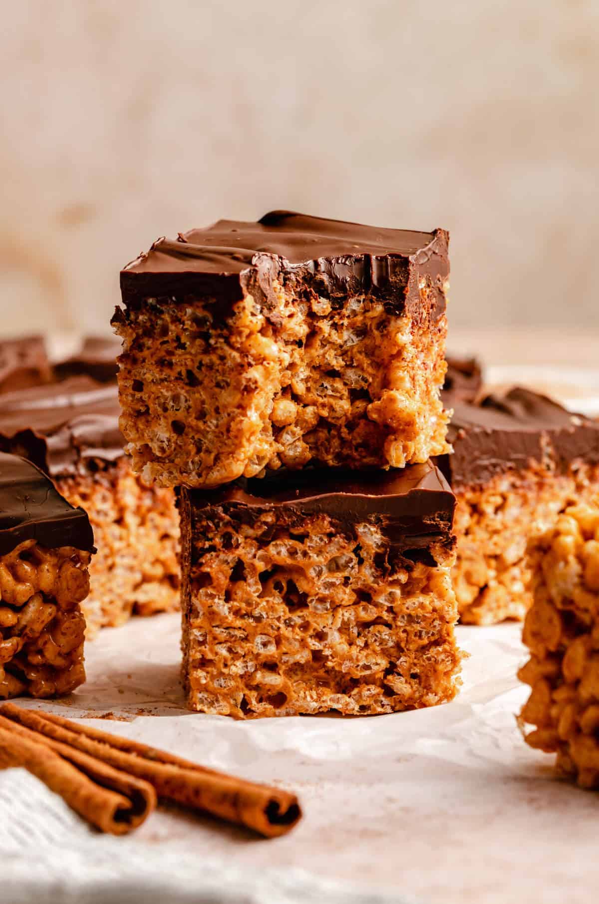 Stack of chocolate covered rice krispie bars in a stack, the top bar has a bite taken out of it.