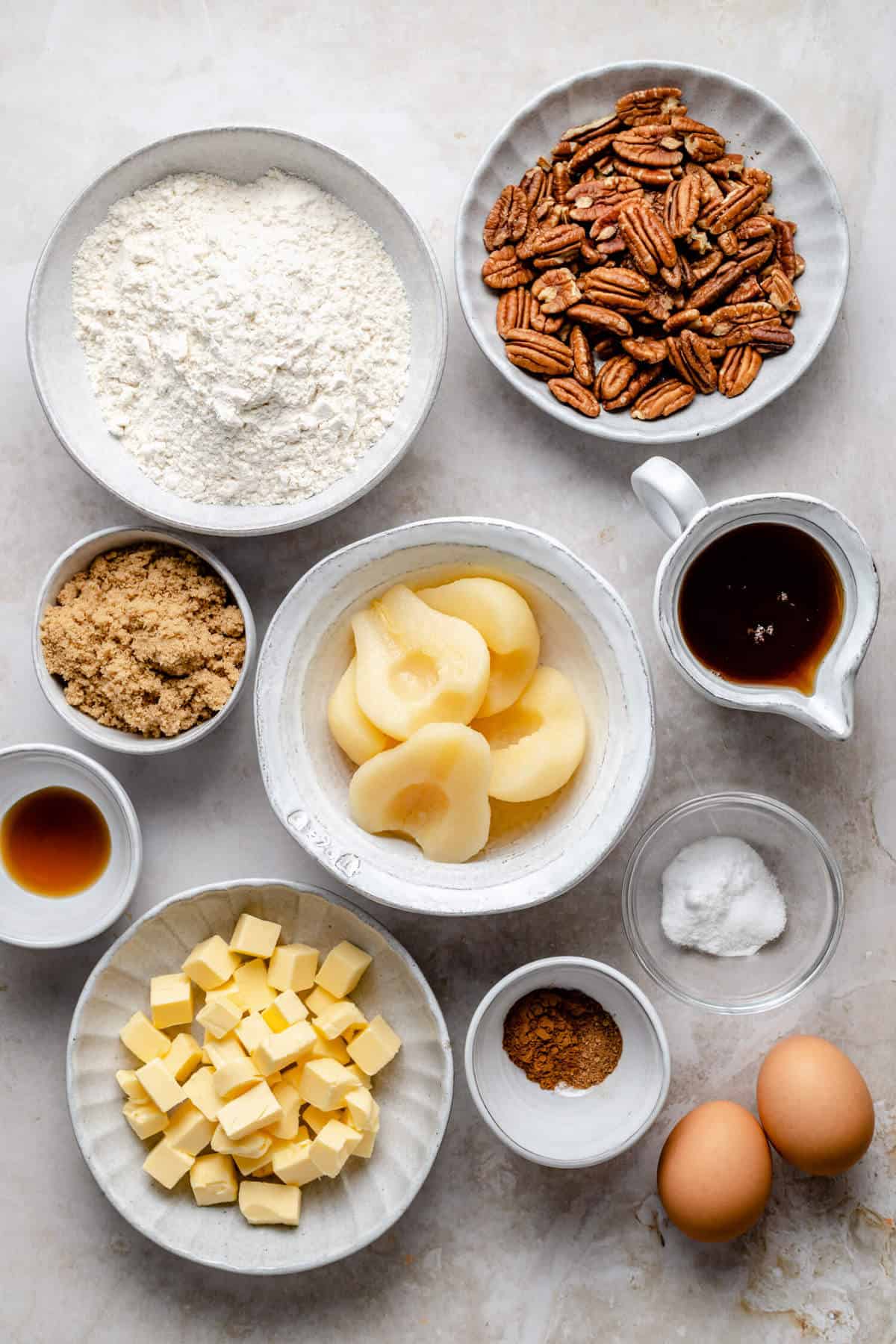 photo of various bowls containing the ingredients from the recipe, including canned pears, pecans, flour, butter and maple syrup