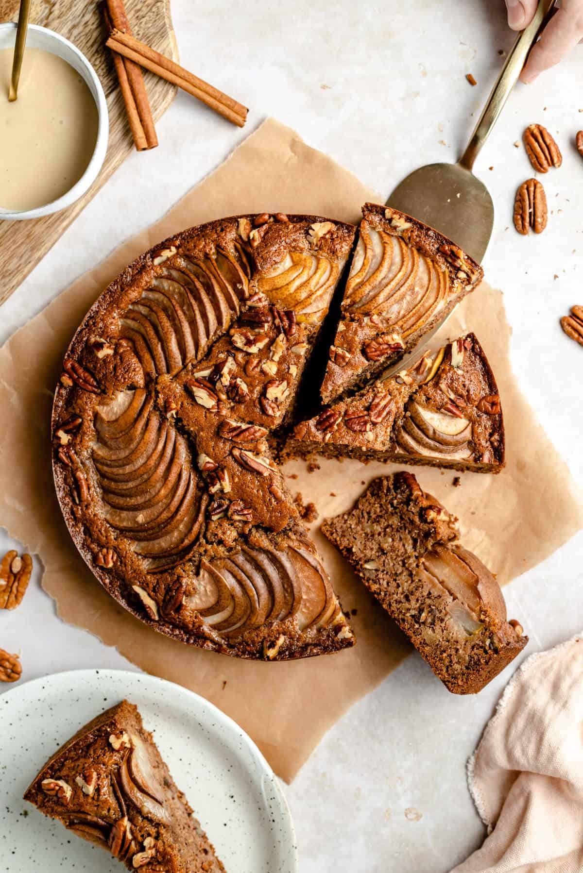 photo of a cake that has been sliced into, a hand holding a cake server is pulling a slice out