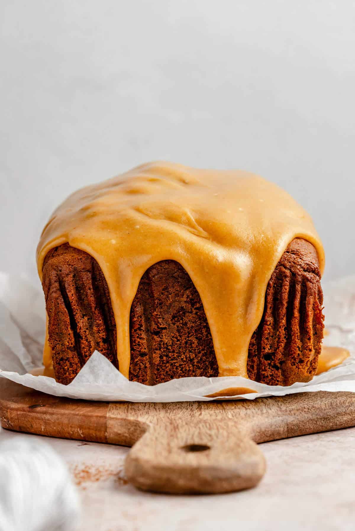 Pumpkin gingerbread on a board with brown butter caramel glaze dripping over the edge.