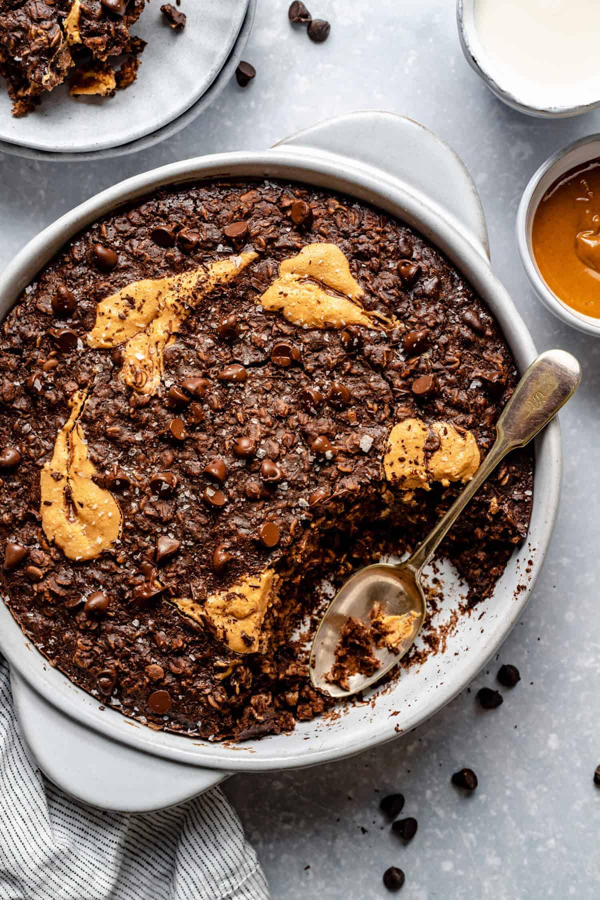 round dish of double chocolate peanut butter baked oatmeal with a scoop taken out and a spoon in the dish