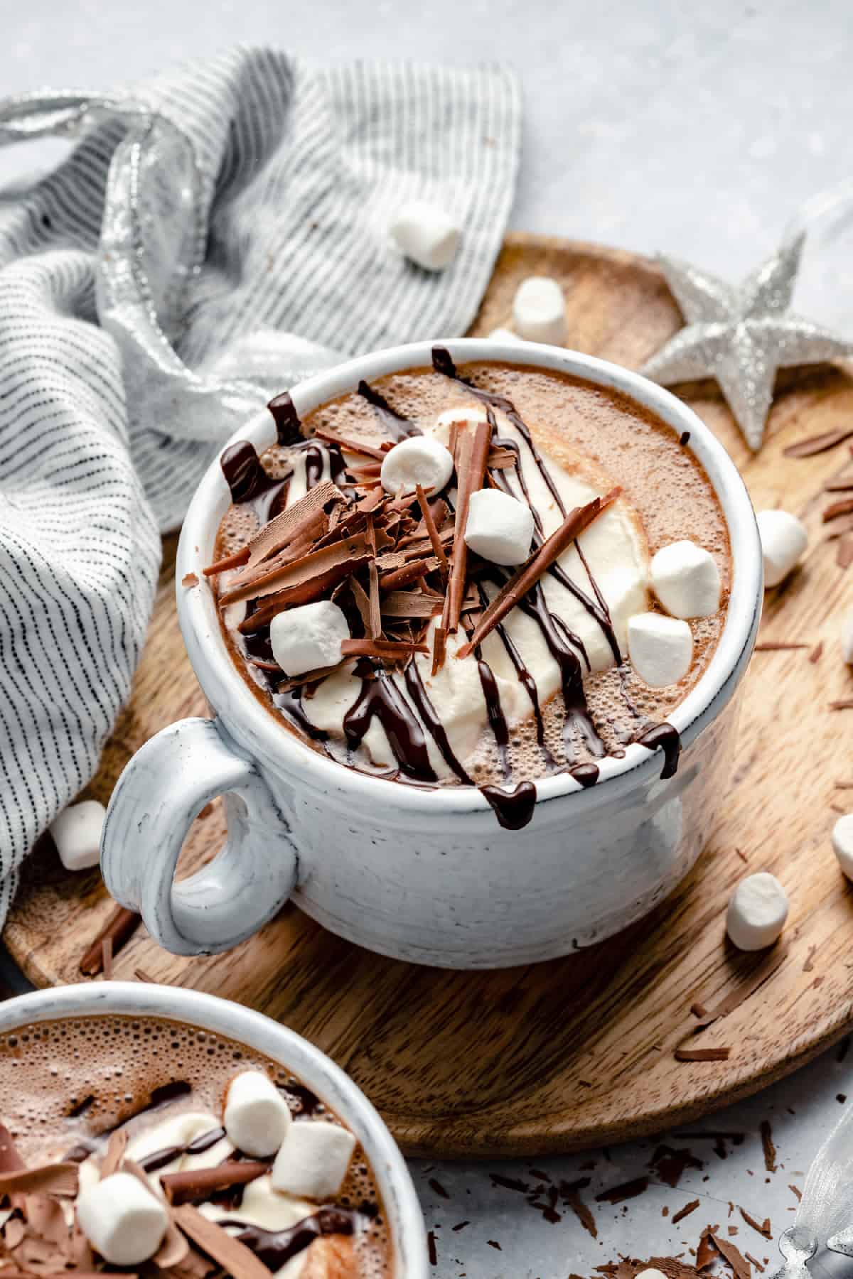 Christmas peppermint hot chocolate in a mug on a board with a napkin and marshmallows around.