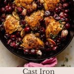 crispy chicken thighs in a skillet surrounded by juicy cherries