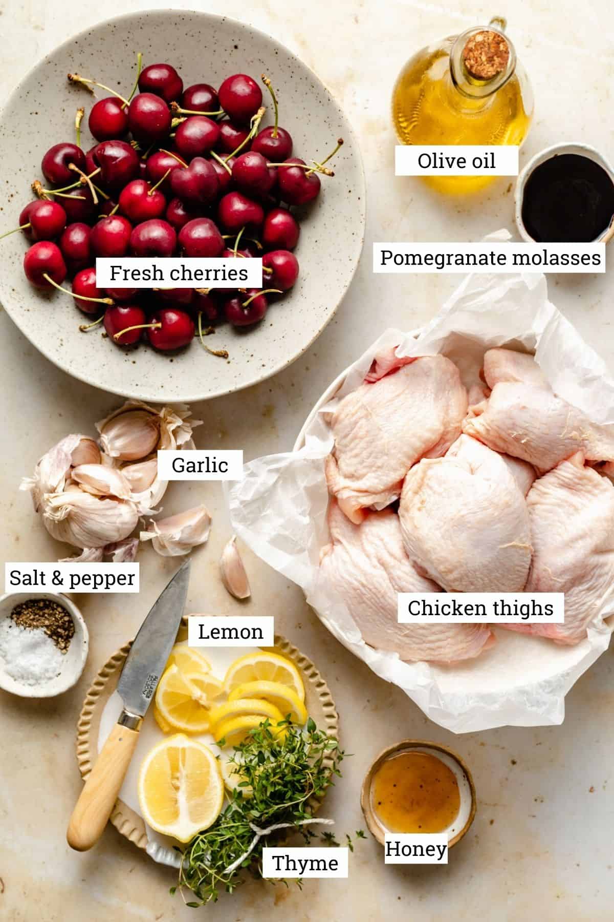 bowls of ingredients including chicken thighs, cherries, garlic, lemon, thyme with labels and on a warm background.