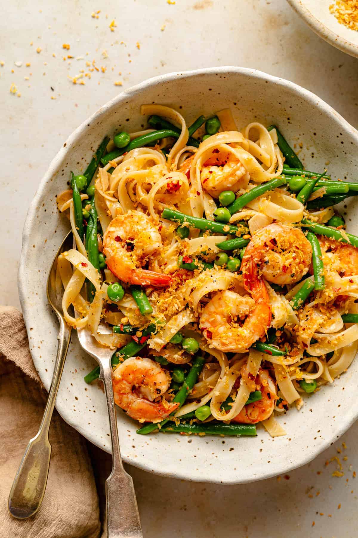 A bowl of lemon garlic shrimp pasta with a breadcrumb topping with a fork.