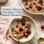A serving of tahini cherry chocolate chip baked oatmeal in a bowl with a newspaper, cherries and a spoon