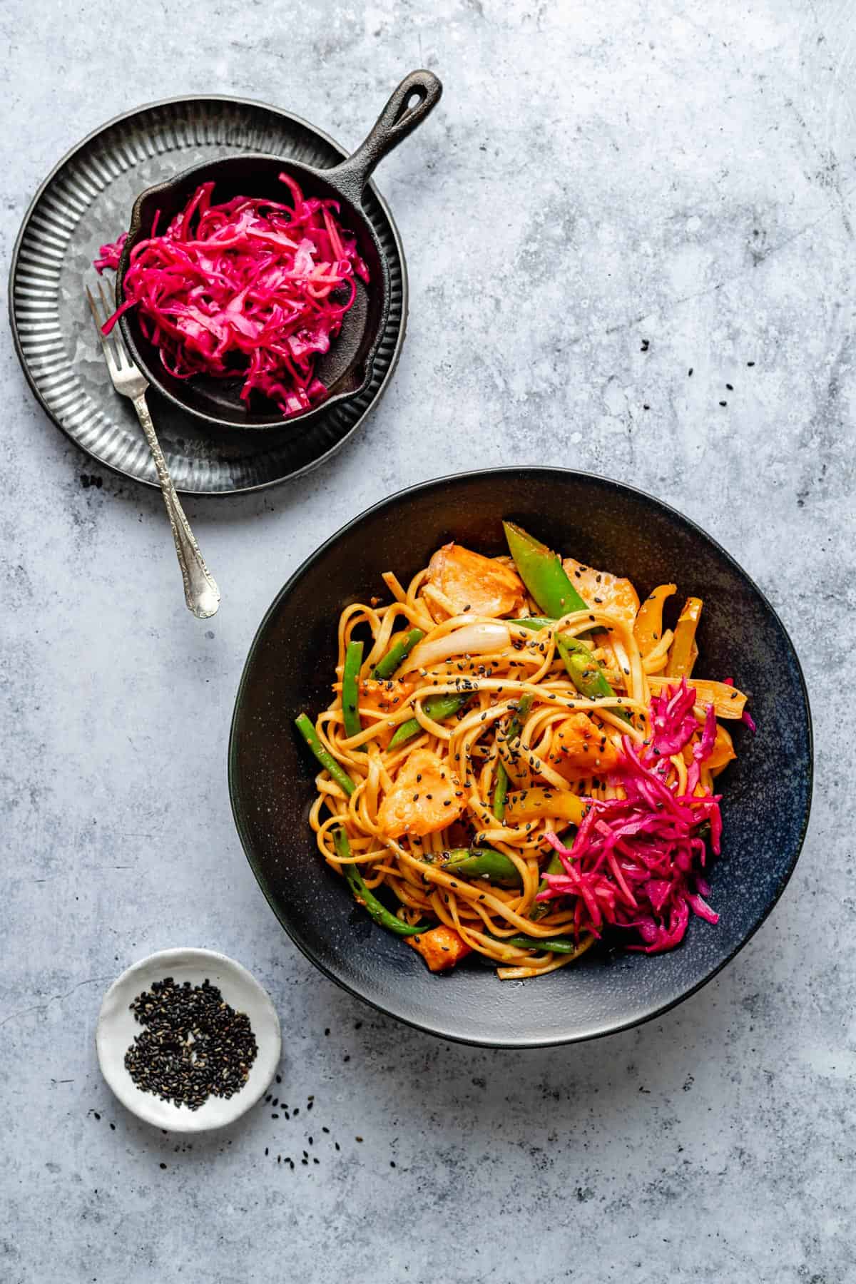 gochujang noodles with salmon in a bowl with a cabbage quick pickle on the top. 