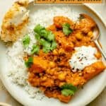 Butternut squash curry served in a bowl on rice with yoghurt, naan and a spoon.