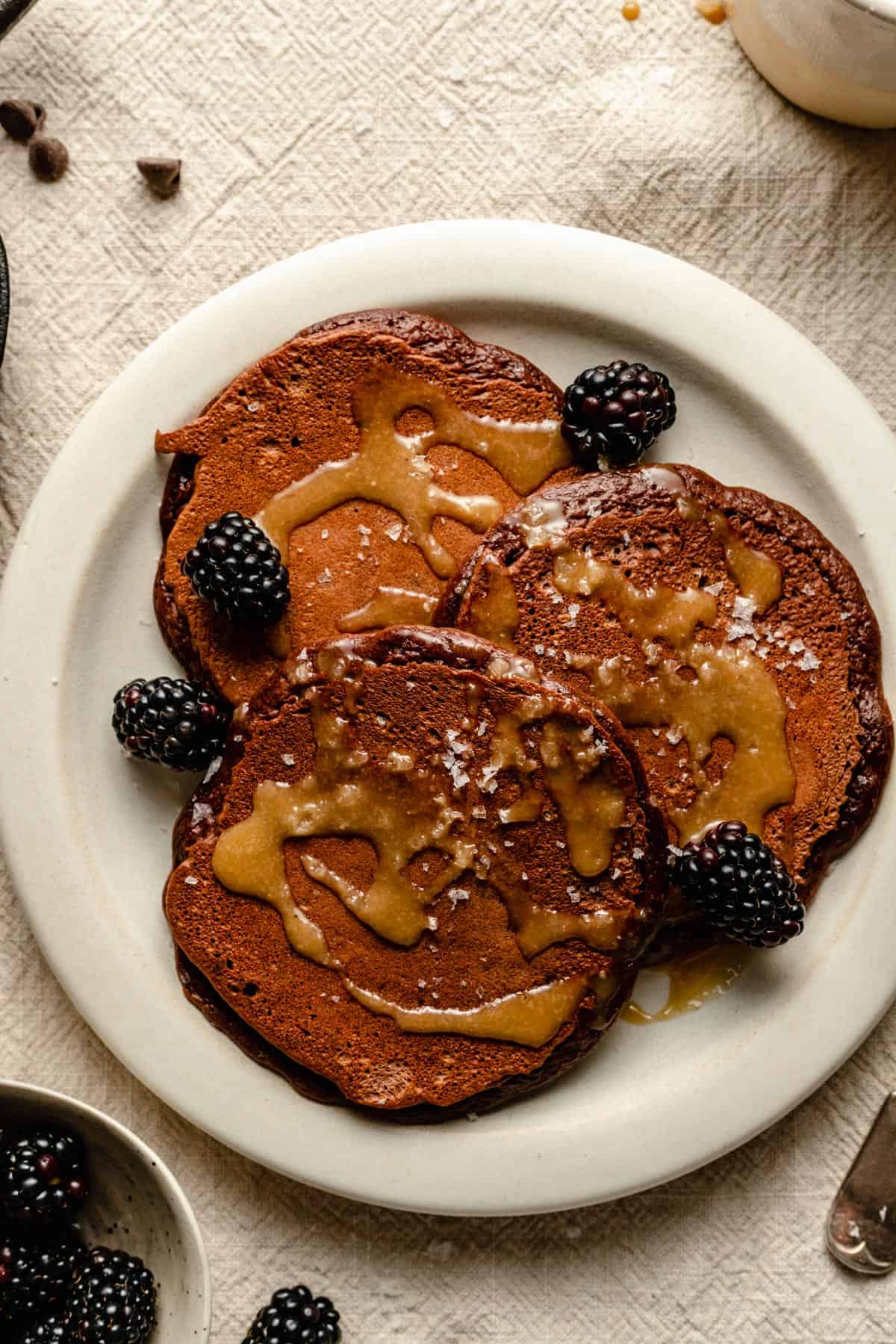 Pancakes topped with syrup, blackberries and flaky salt. 