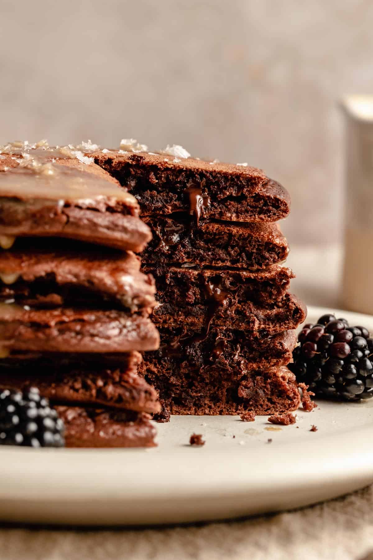 A stack of double chocolate pancakes with a chunk cut out and chocolate chips melting out.