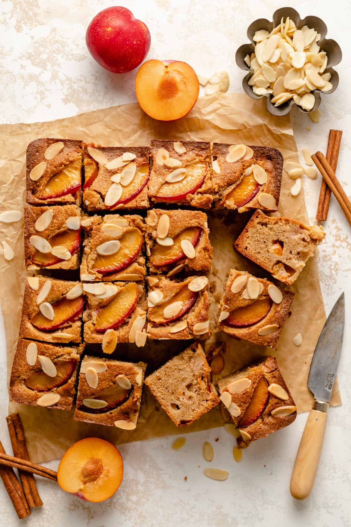 Plum and almond cake slices turned up in an array with a knife nearby.