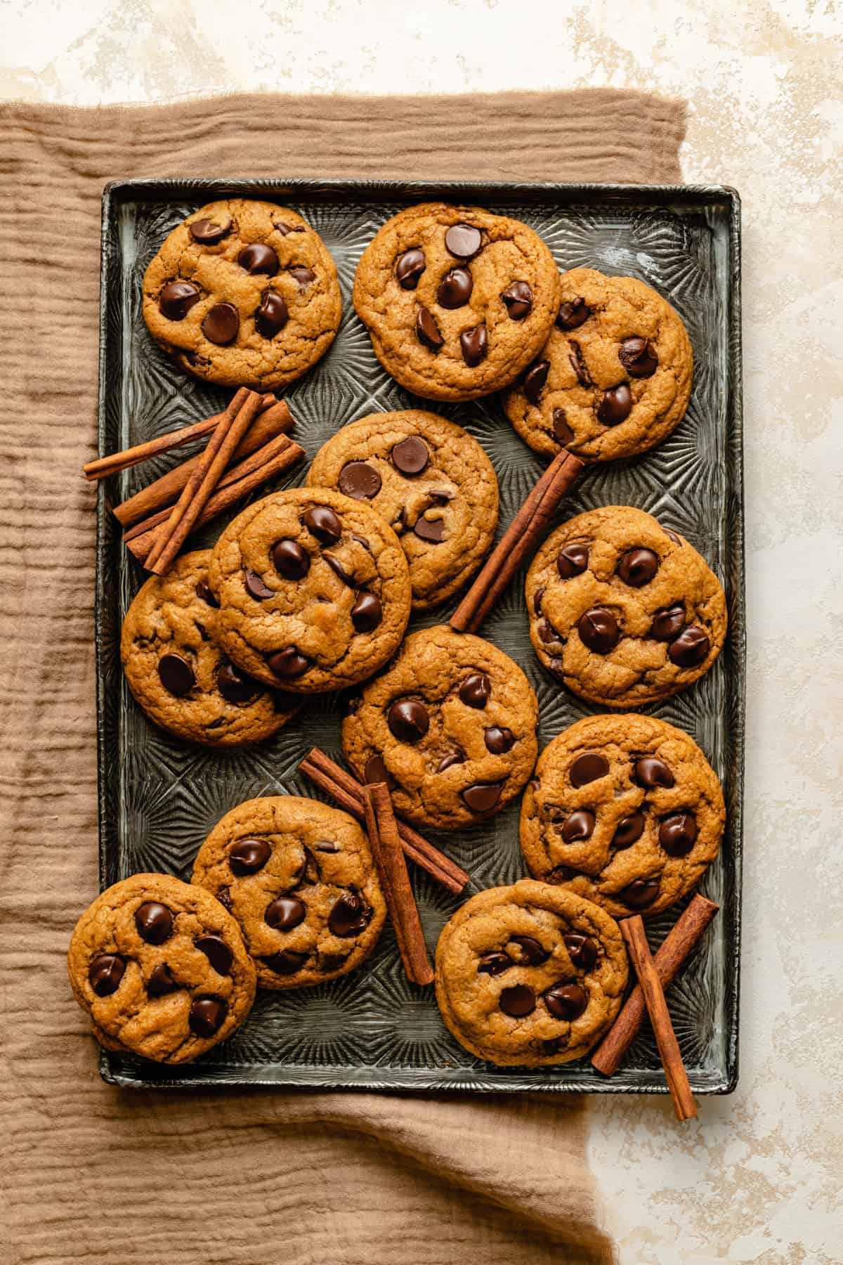 A tray of chewy cookies with cinnamon sticks scattered amongst them.