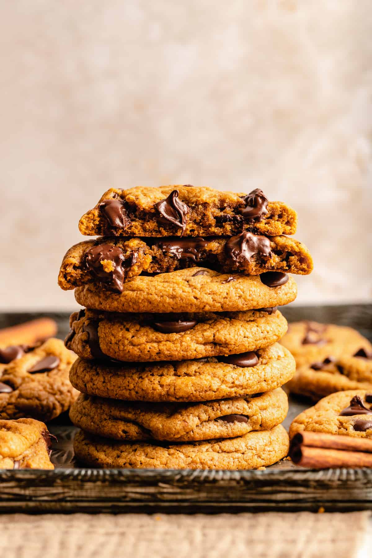 A stack of pumpkin cookies with a broken cookie on top with gooey molten chocolate chips.