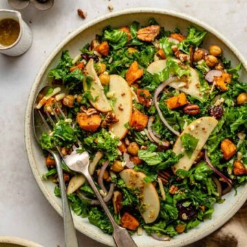 Sweet potato kale salad with forks, napkin and dressing to the side.