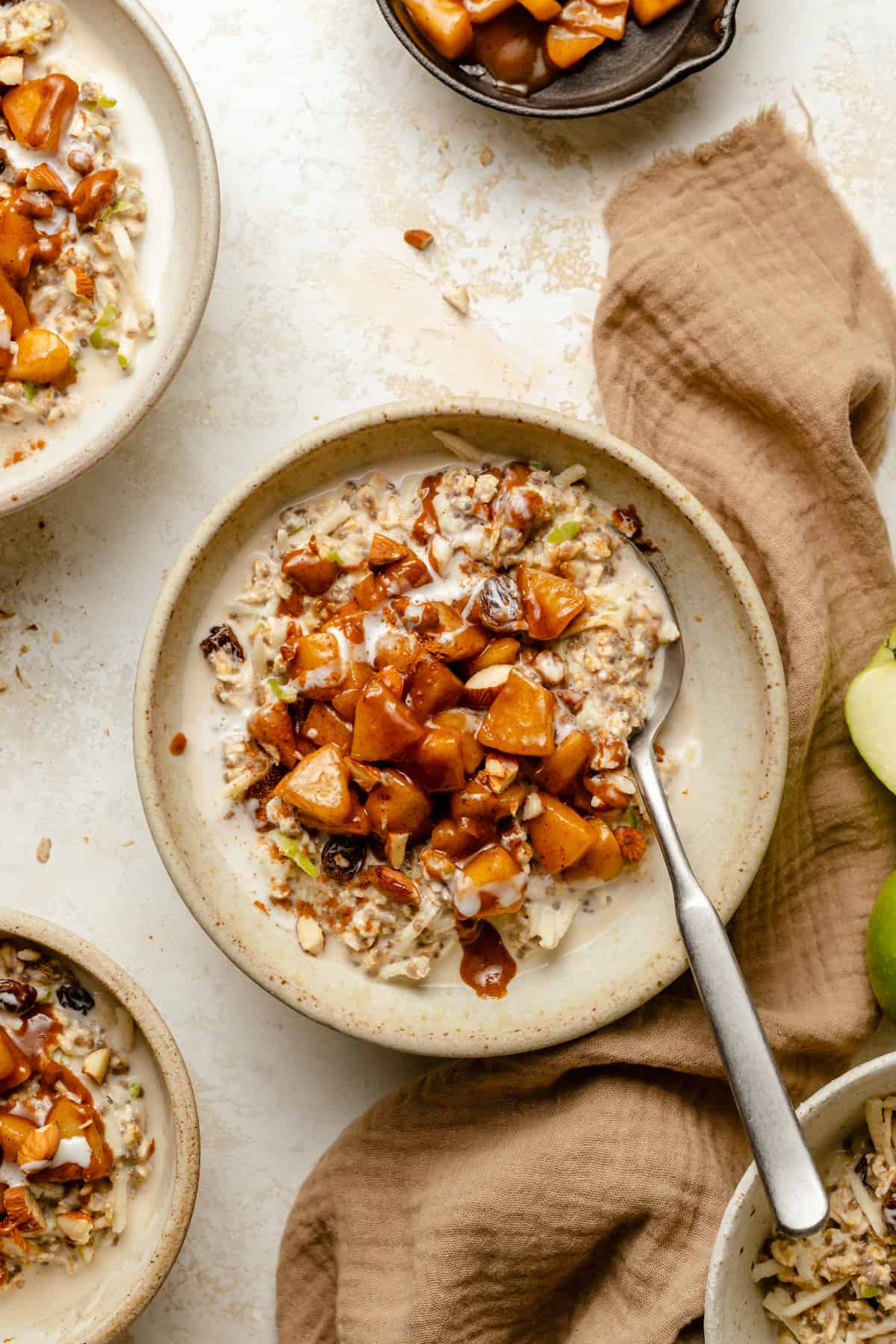 Apple cinnamon overnight oats in a bowl with apple cinnamon topping with a spoon and napkin. 