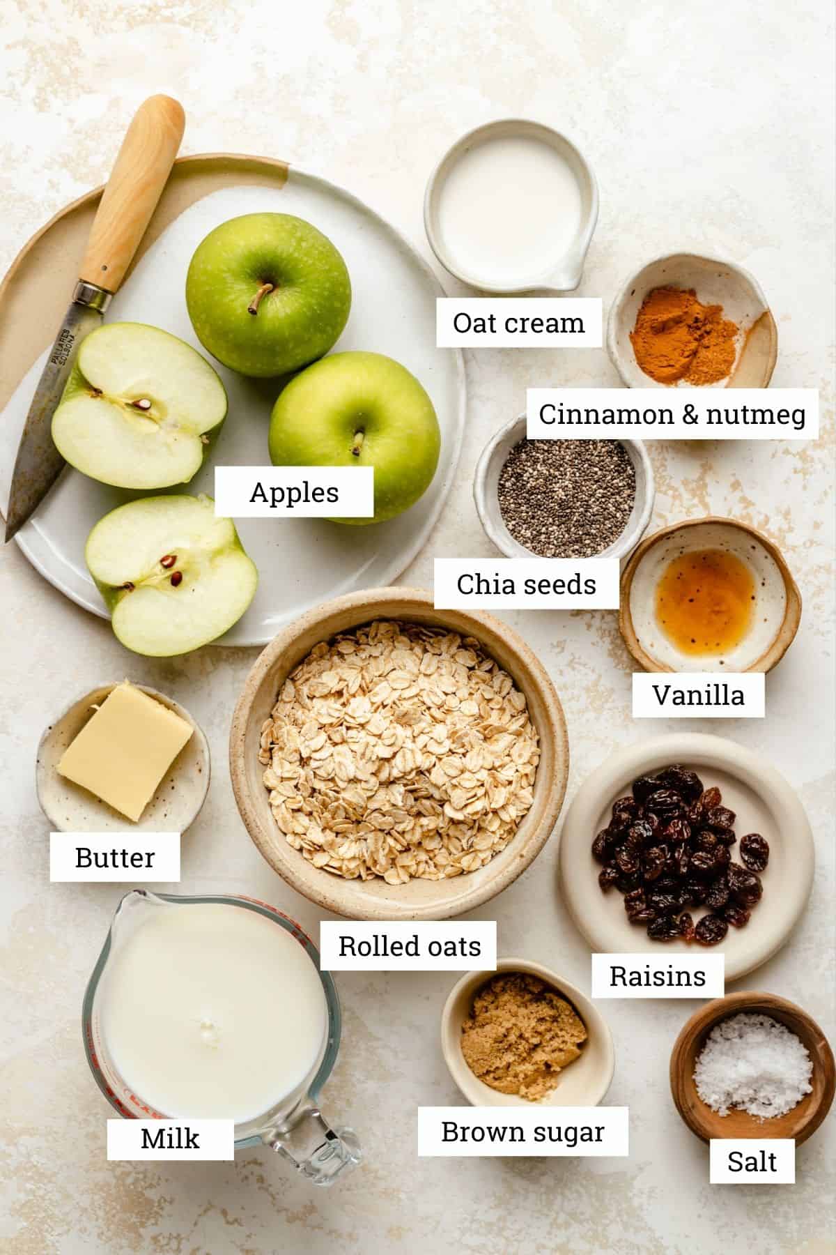 Ingredients in various bowls including: apples, oat cream, oats, milk, raisins, sugar and spices.