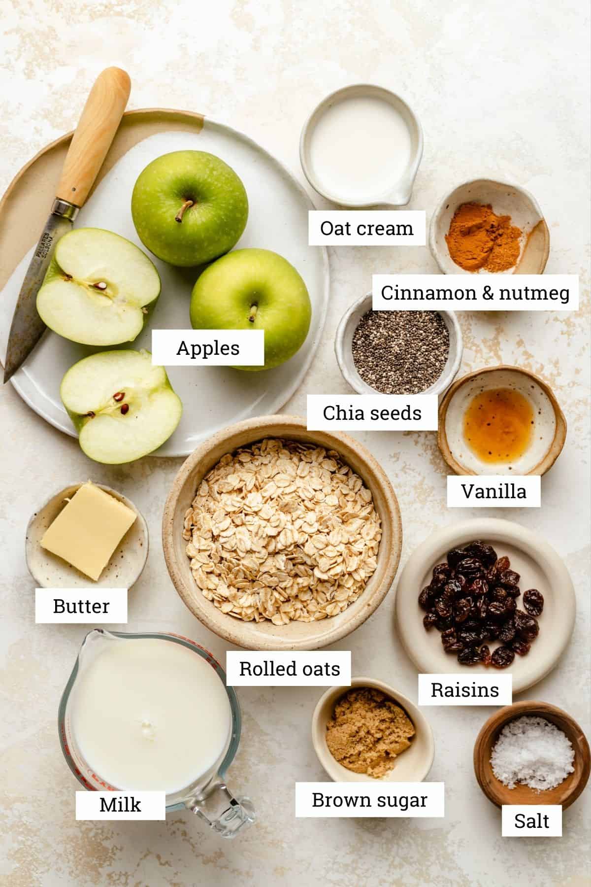 Ingredients in various bowls including: apples, oat cream, oats, milk, raisins, sugar and spices. 