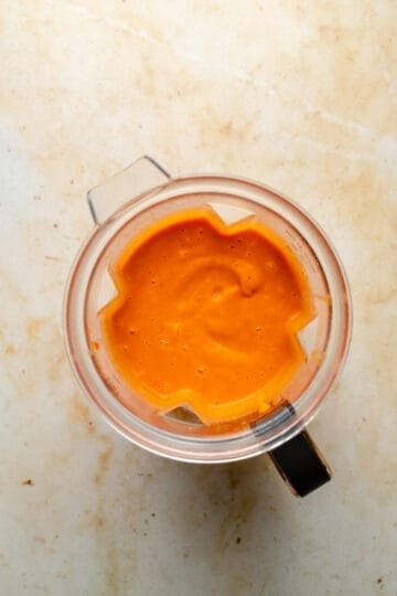 Butternut squash soup blended smooth in a blender jug.