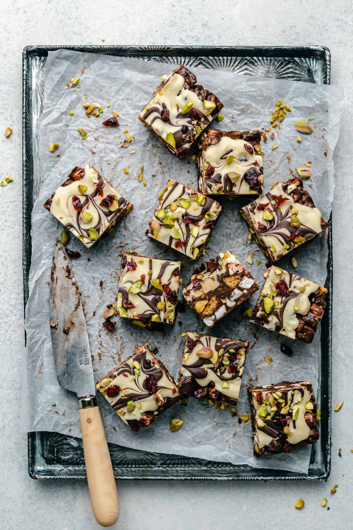 An array of the chocolate no bake slices on a tray with parchment paper underneath and a knife to the side.