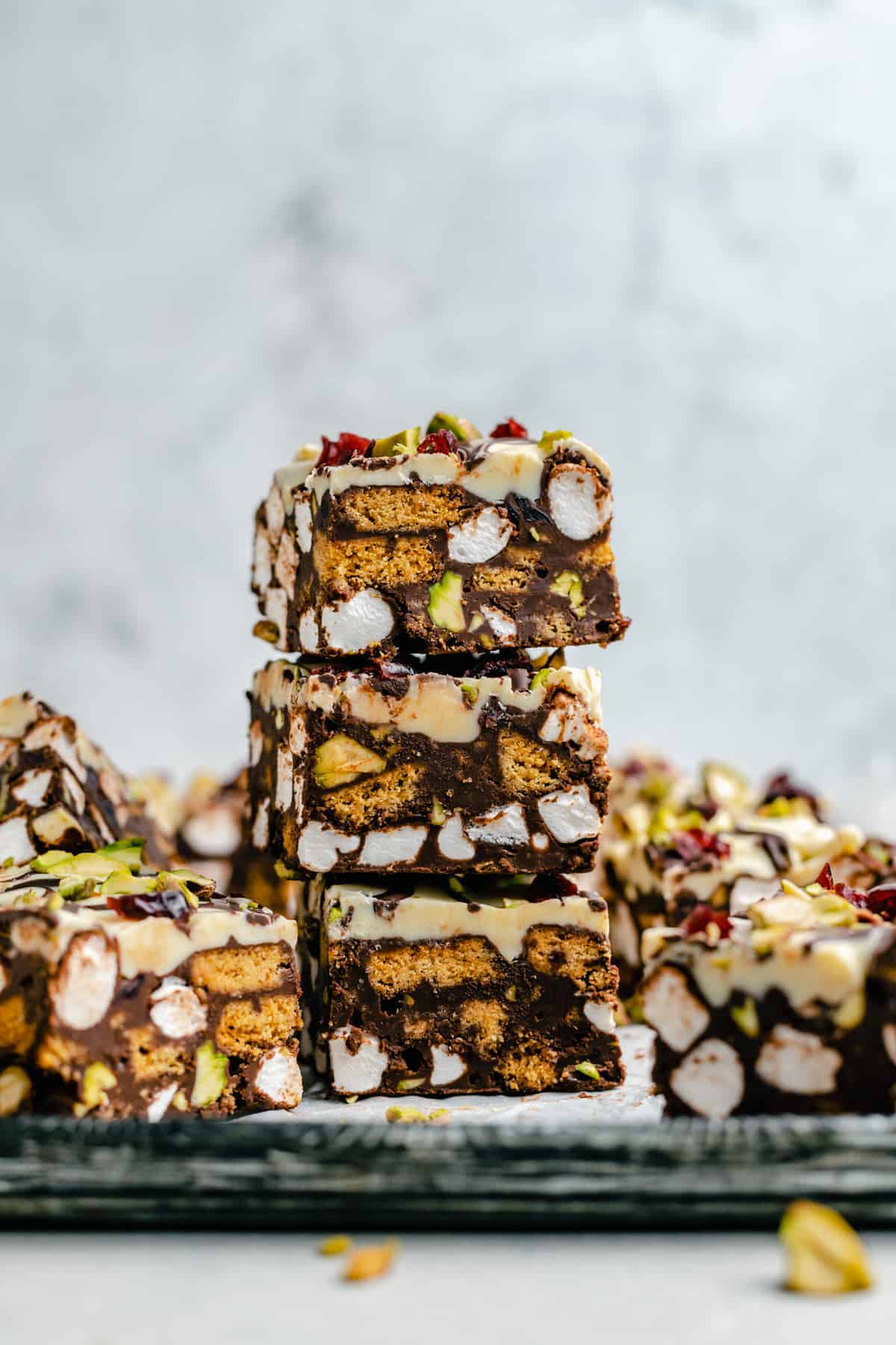 A stack of rocky road on a tray surrounded by other slices. You can see layers of marshmallow, chocolate and biscuit.