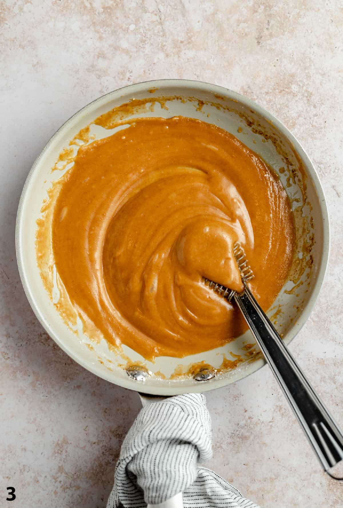 Finished brown butter caramel glaze in a skillet with a whisk.