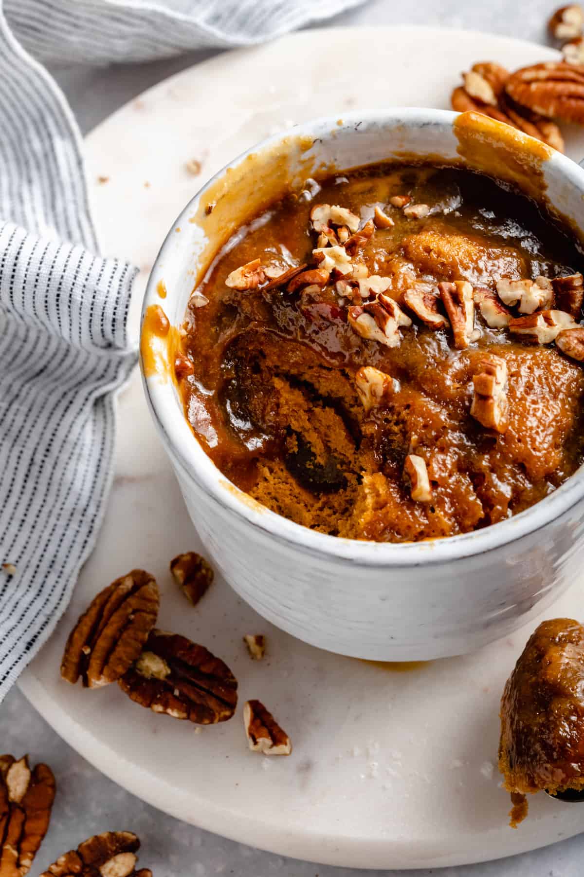 Close up showing the inside of the mug cake with toffee sauce oozing with chopped nuts on top.