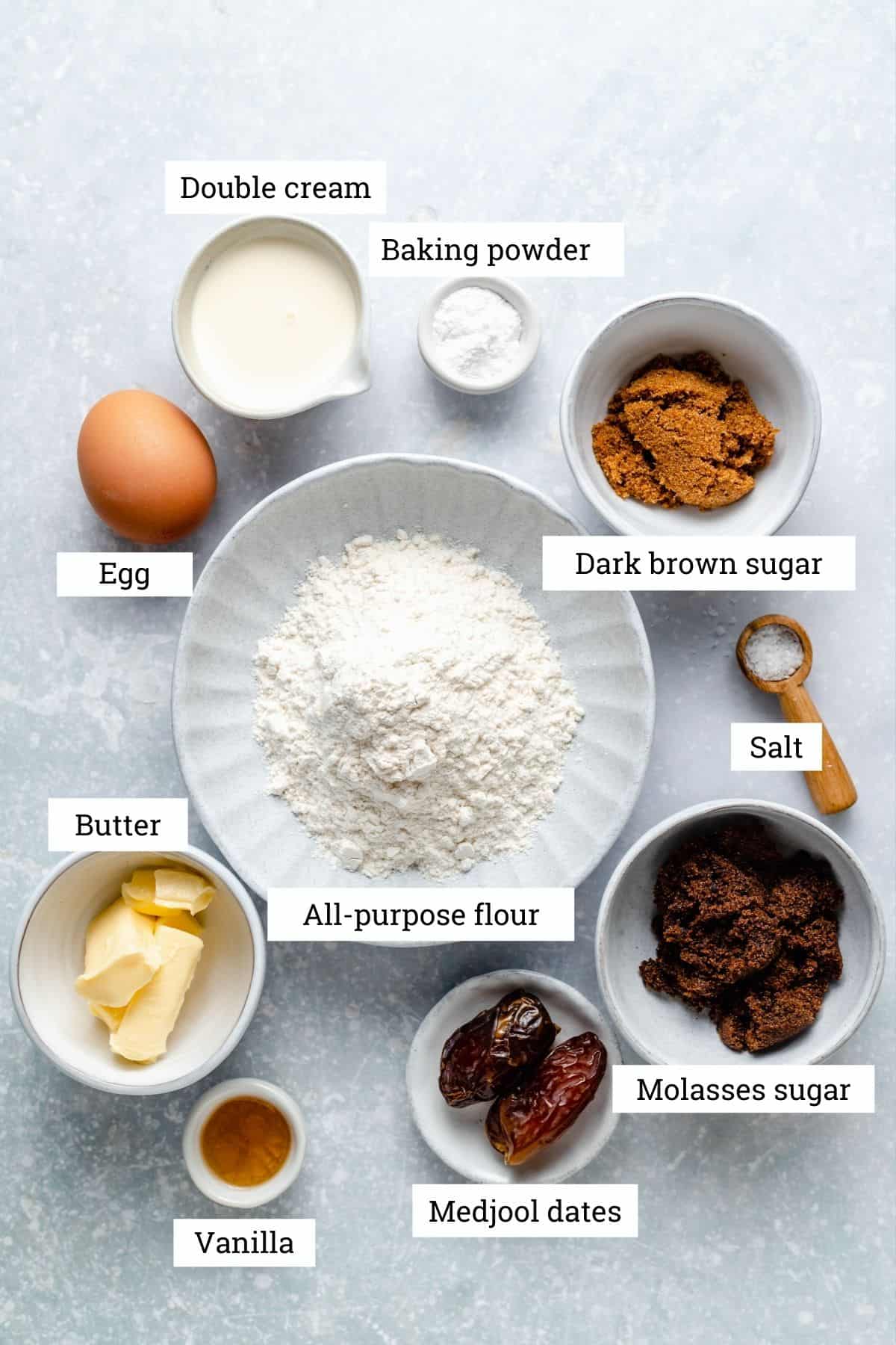 Ingredients for the sticky toffee mug cake in bowls: flour, sugar, cream, butter, egg, medjool dates, vanilla and baking powder.
