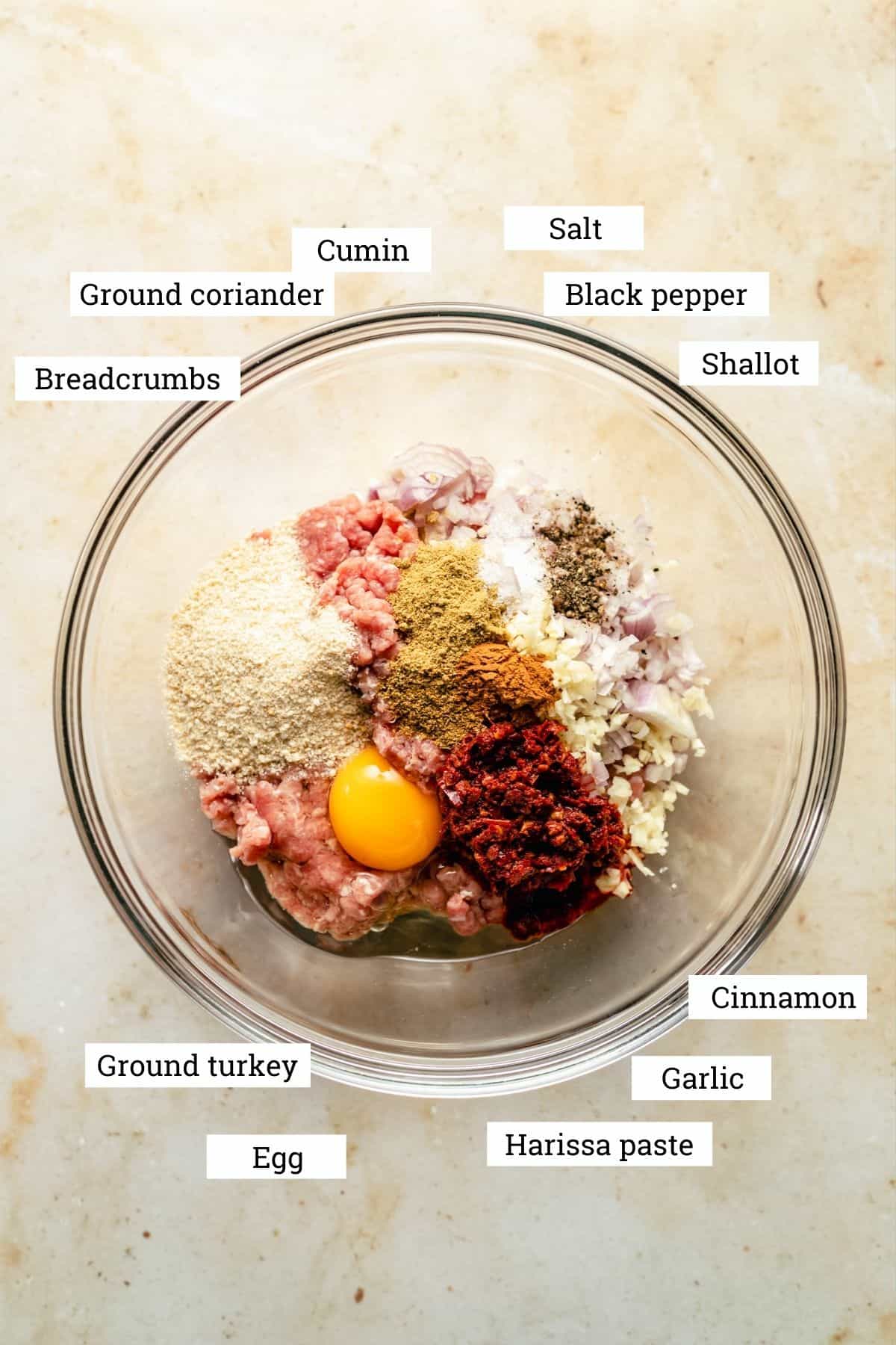 The ingredients for the baked spicy turkey meatballs in a bowl including turkey mince, harissa and spices.