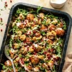 Baked spicy turkey meatballs in a baking tin with roasted cauliflower, dressing and arugula.
