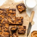 Biscoff brownies sliced up with a knife and a glass of milk on the side.