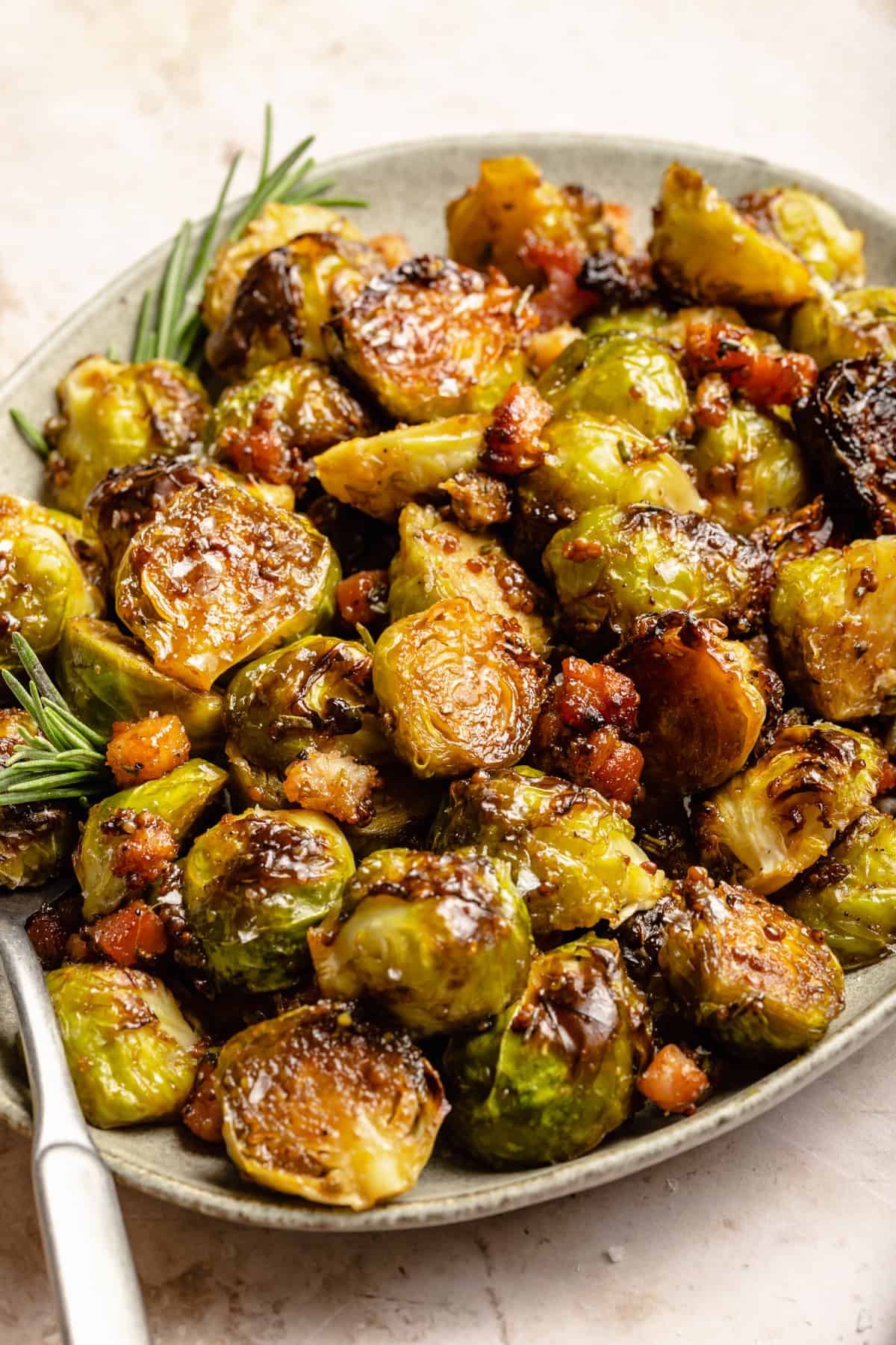 Caramelized brussels sprouts with bacon and maple on a plate with a spoon.